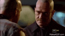 two men are standing next to each other and talking to each other . one of the men is wearing glasses .