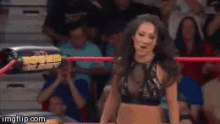 a woman is standing in a wrestling ring with a referee behind her .