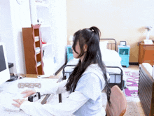 a woman sits at a desk in front of a clock that says 8:08