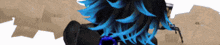 a person with blue hair is standing in front of a pile of cards .
