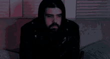 a man in a hooded jacket covers his face with his hand