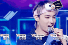 a young man singing into a microphone with a lullaby sticker on his headband