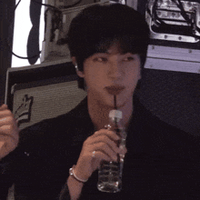 a man drinking from a bottle with a straw and a sign behind him that says ' a ' on it