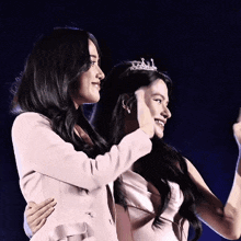two women standing next to each other one wearing a tiara on her head