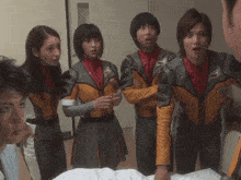 a group of people are standing around a bed and one of them has the letter t on their uniform