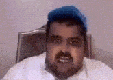 a man wearing a white shirt and a blue hat is sitting in a chair