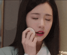 a woman is applying makeup to her face with a cotton pad
