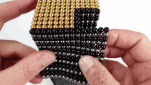 a person is holding a stack of gold and black beads in their hands