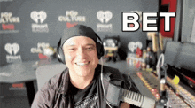 a man wearing headphones is smiling in front of a microphone with the word bet written above him