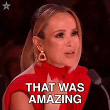 a woman in a red dress is speaking into a microphone and the words that was amazing are above her