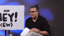 a man sitting in front of a sign that says hey crew