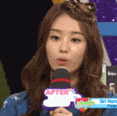 a woman holding a microphone with a sign that says after school club on it