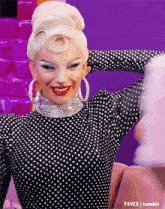 a drag queen is wearing a black and white polka dot dress and earrings .
