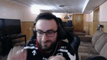 a man wearing glasses and headphones is sitting in a chair in a living room .