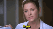 a woman in a lab coat is holding a pair of stethoscopes and singing .