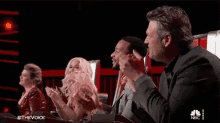 a group of people sitting in front of a screen that says #thevoice