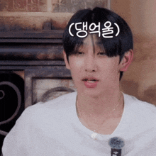 a young man wearing a white t-shirt and a necklace has korean writing on his forehead