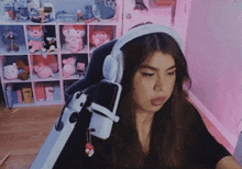 a girl wearing headphones is sitting in front of a microphone in a room .