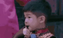 a little boy is eating a candy bar while sitting on a chair .