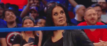 a woman is standing in a wrestling ring while another woman stands in the background .