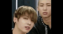 two young men are standing next to each other and one of them is making a face .