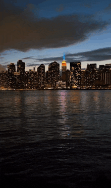 the empire state building is lit up at night with a blue sky in the background