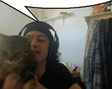 a woman wearing headphones holds a cat in her arms