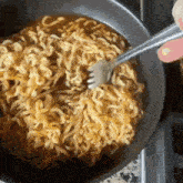 a person is stirring noodles with a fork in a bowl