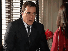 a man in a suit and tie is talking to a woman in a red jacket