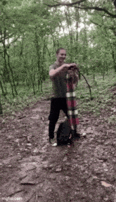a man is standing in the woods holding a scarf .