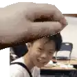 a person is holding a piece of paper over a young boy 's head .