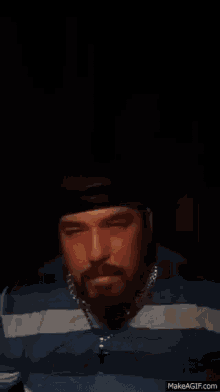a man with a beard and a hat is making a fist with his hands .