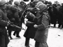 a black and white photo of soldiers standing in the snow