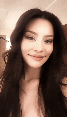 a woman with long dark hair looks at the camera and smiles