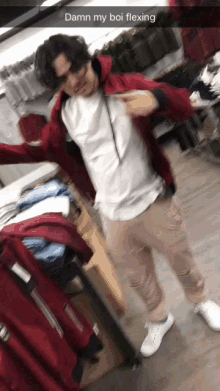 a man wearing a red jacket and a white shirt is flexing in a store