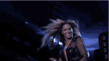 a woman with long hair is dancing on a stage in front of a blue light