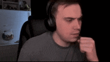 a man wearing headphones is sitting in a chair with his hand to his mouth