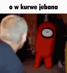 a man is looking at a red among us character in a dark room .