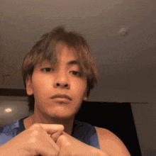 a young man is making a funny face with his hands folded in front of his face