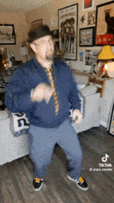 a man in a hat and tie is dancing in a living room .