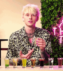 a man in a leopard print shirt holds a shot glass in his hand