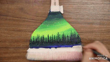 a person is painting the aurora borealis on a broom with the words made in animotica at the bottom