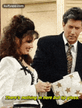 a man and a woman are standing next to each other and the woman is holding a piece of paper with stars on it .
