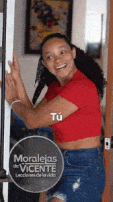 a woman in a red shirt is standing in front of a poster that says moralejas de vicente