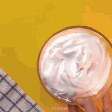 a person is holding a bowl of whipped cream with the words mr.cakes written below it