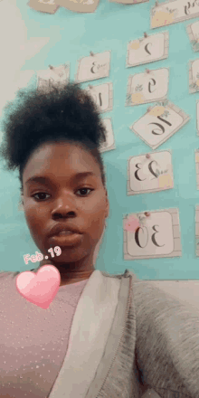 a woman is taking a selfie in front of a bulletin board with the date february 19 on her chest .