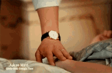 a man wearing a watch and a ring is touching a woman 's arm .