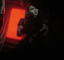 a woman is pointing a gun at the camera in a dark room .