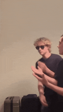 two men wearing sunglasses are standing next to each other in a room