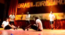 a group of people are dancing in front of a sign that says brasil circus